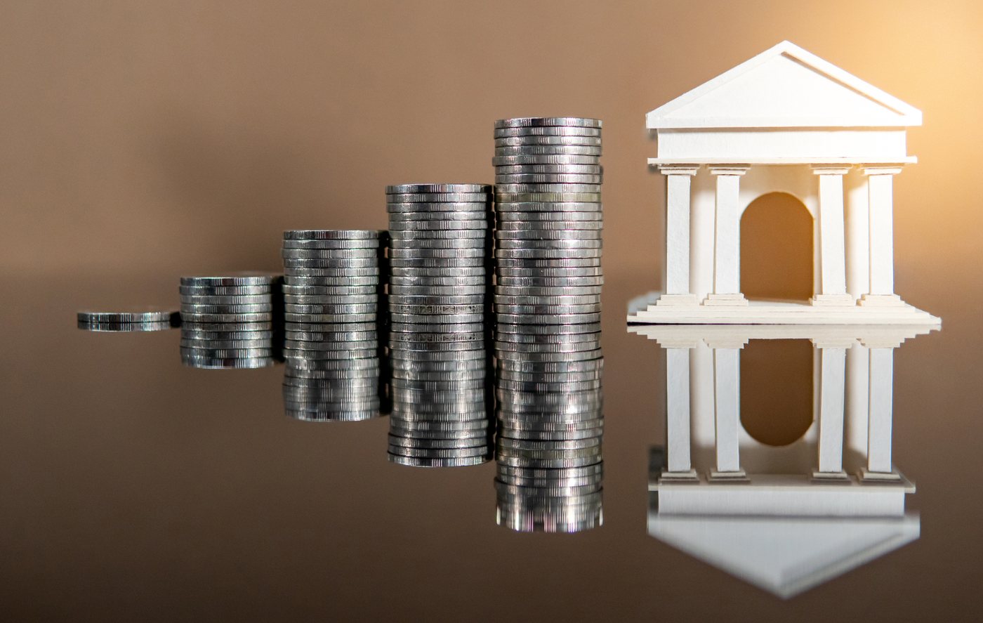 Pièces empilées et bâtiment bancaire illustrant les métiers de la finance