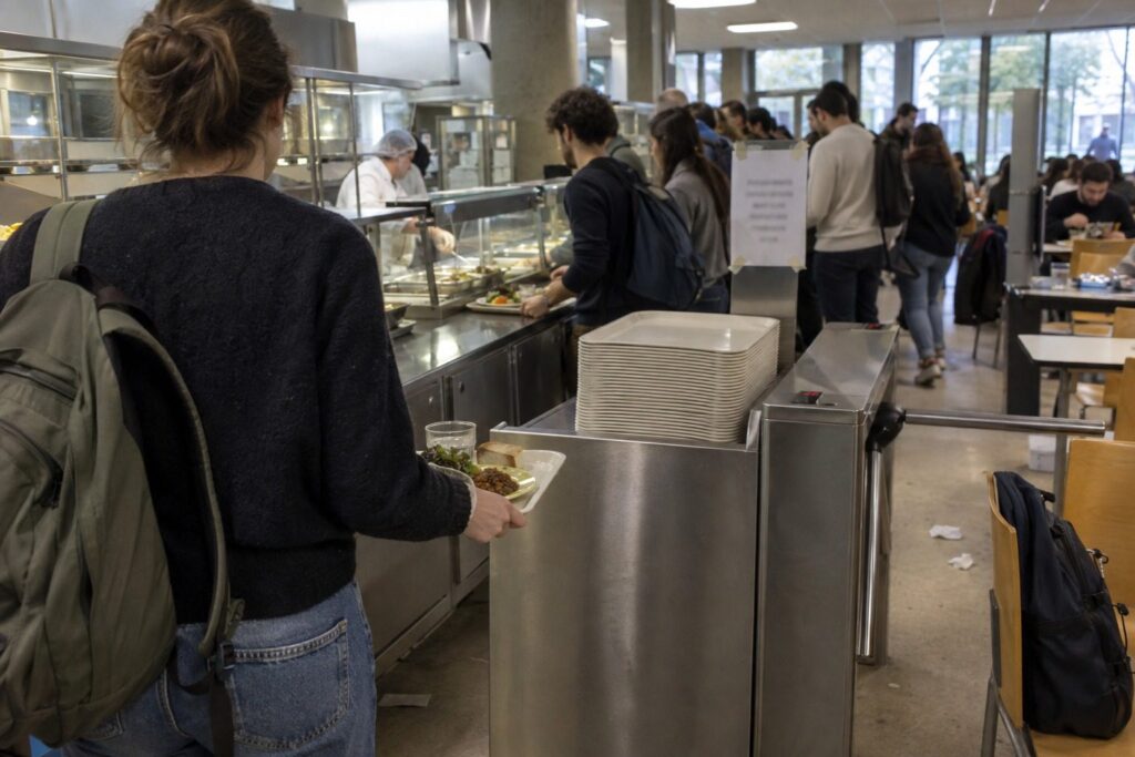 Étudiants adultes de dos avec plateaux-repas faisant la queue au restaurant universitaire