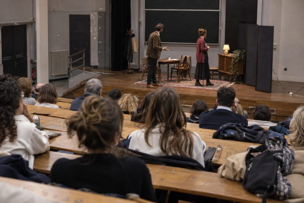 Amphithéâtre universitaire, étudiants de dos assistant à une pièce sur les violences sexistes